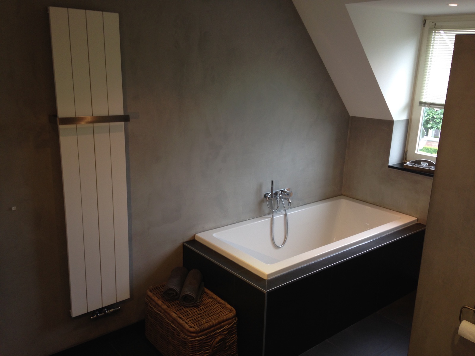 Betonlook badkamer met bad en designradiator in Breda
